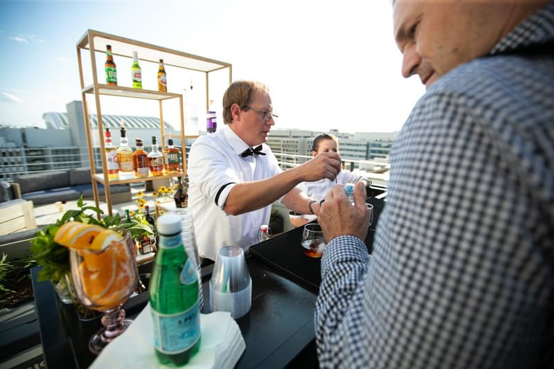 Bartender serving guests at an outdoor rooftop bar setup